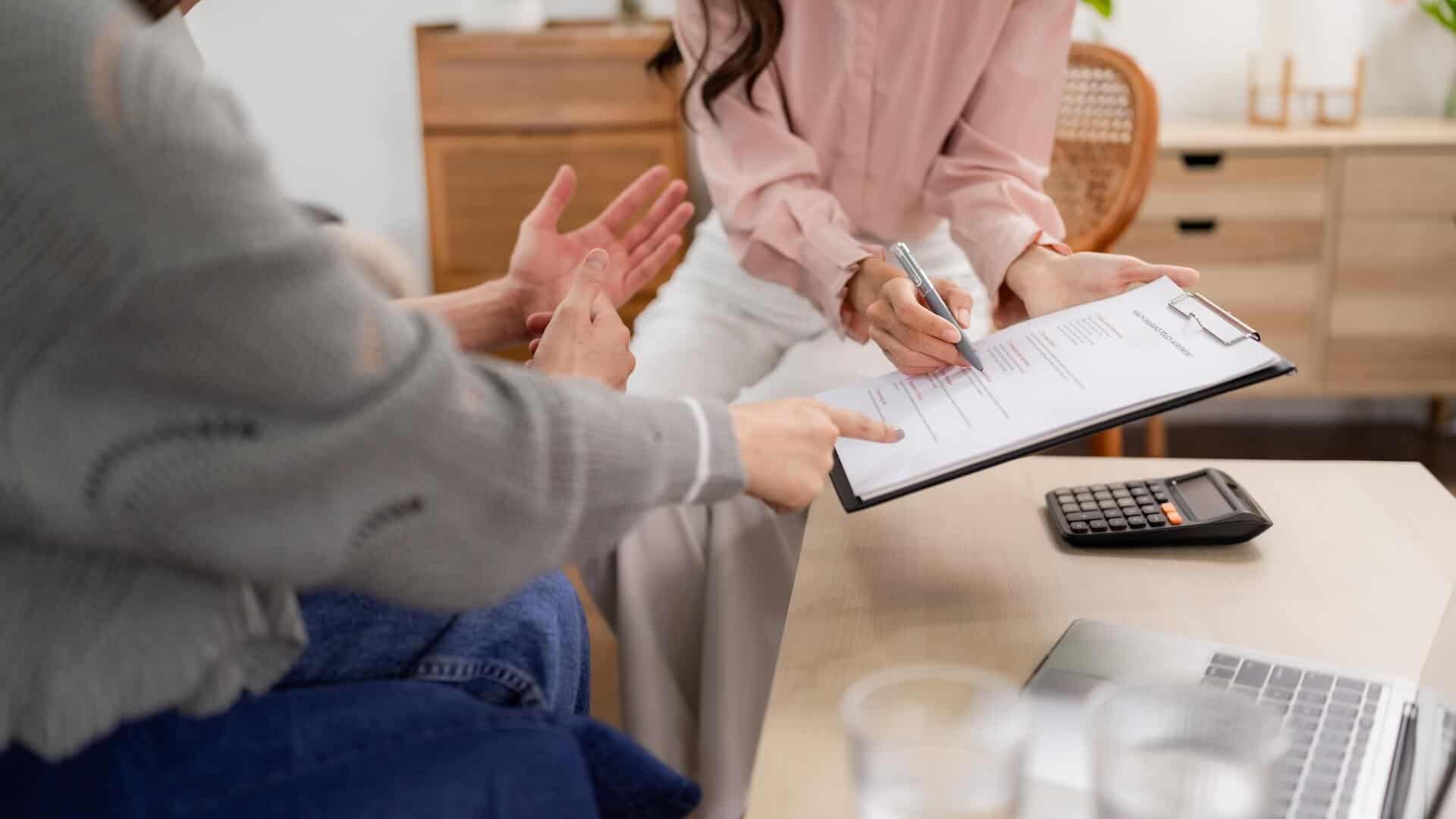 Two people reviewing paperwork with a calculator